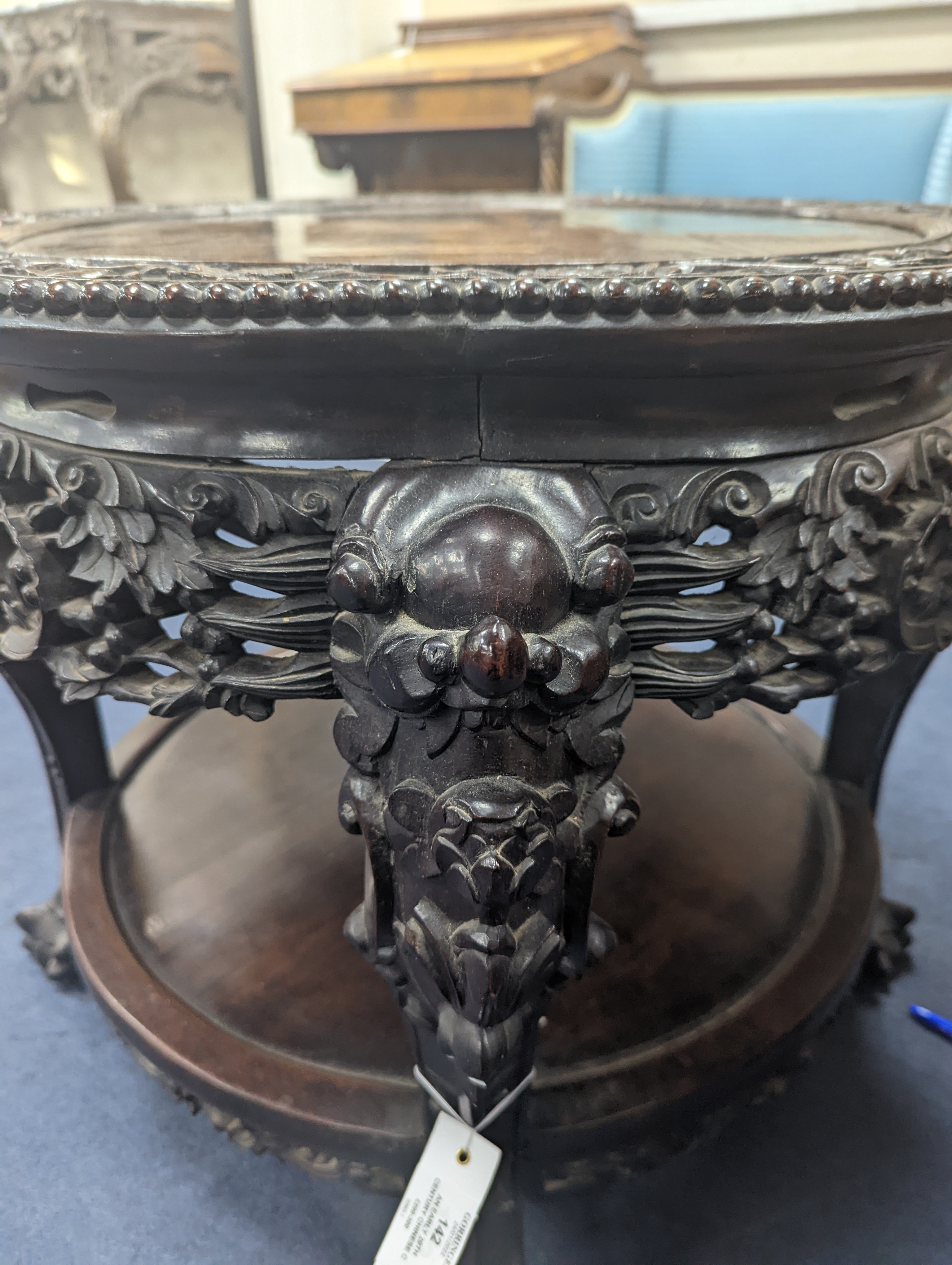 An early 20th century Chinese carved hardwood two tier table, diameter 64cm, height 56cm